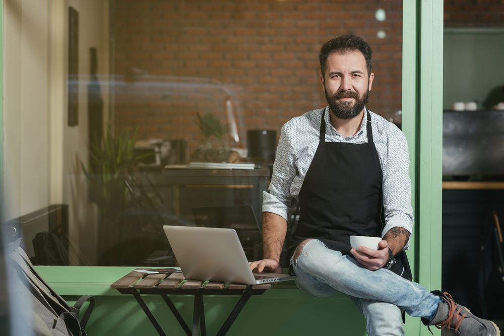 Cafe owner working on a laptop to grow their guest list